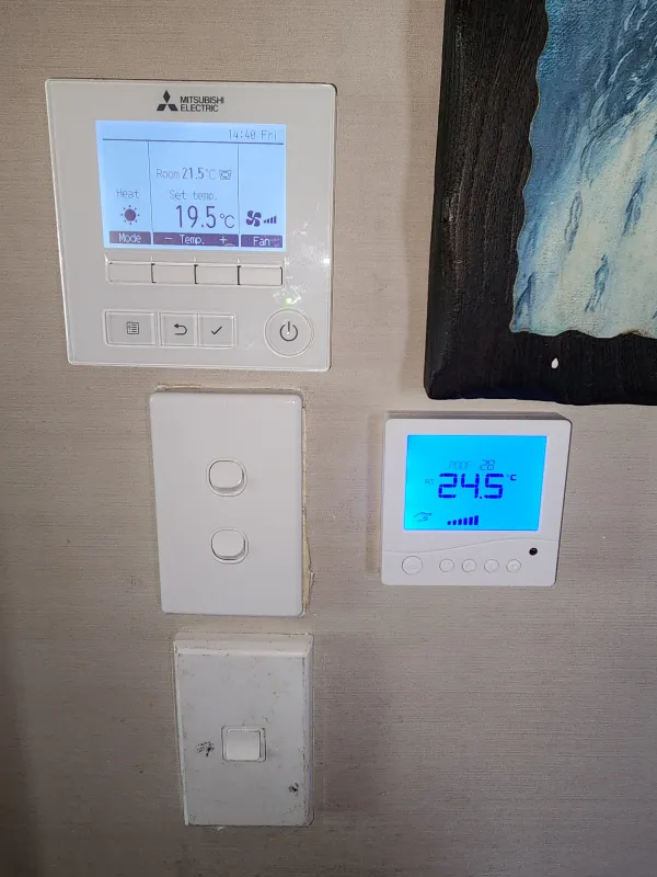 Mitsubishi Electric wall controller, light switches and a blue ventilation display on a white wall
