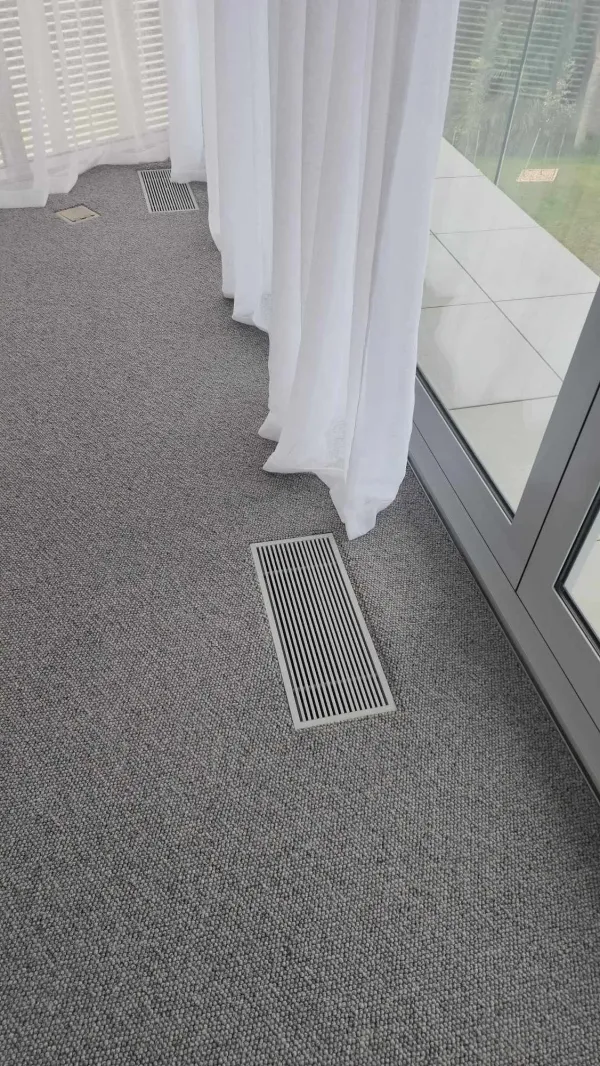 Rectangular floor grille outlet set into timber flooring
