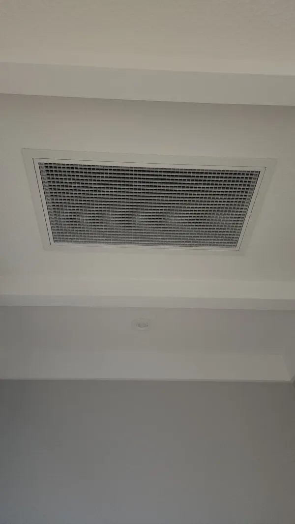 Ceiling diffuser and return grille positioned in a bedroom