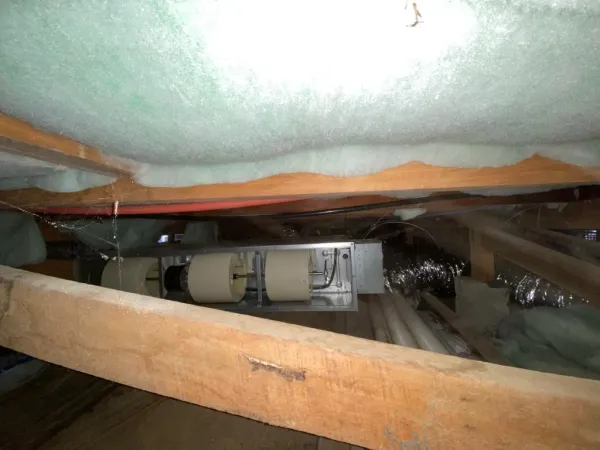Ducted heat pump indoor unit secured among roof trusses