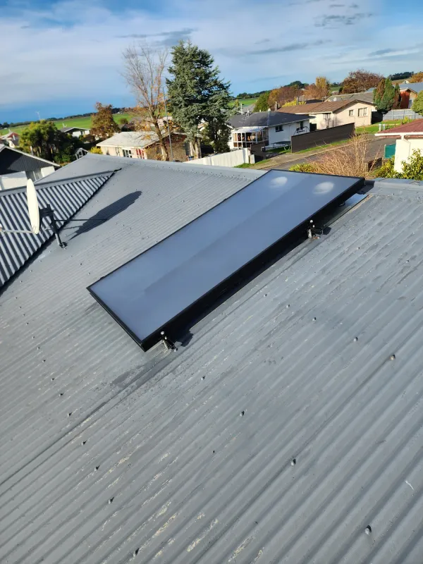 Solar air panel on a terracotta tiled roof above a ducted heating install