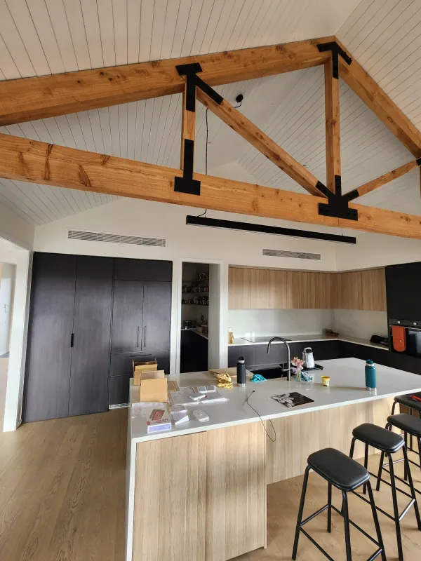 Open plan kitchen under a raked timber ceiling with a slim ducted outlet