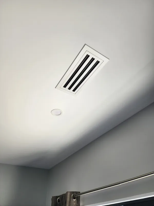 Narrow three slot diffuser set into a white ceiling