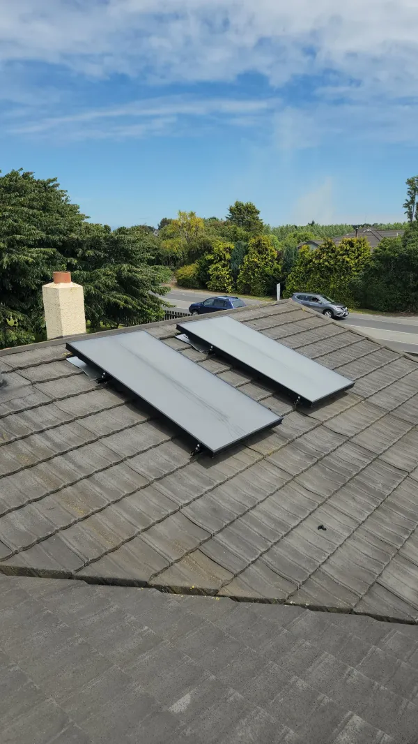 Two solar air panels side by side on a grey concrete tile roof