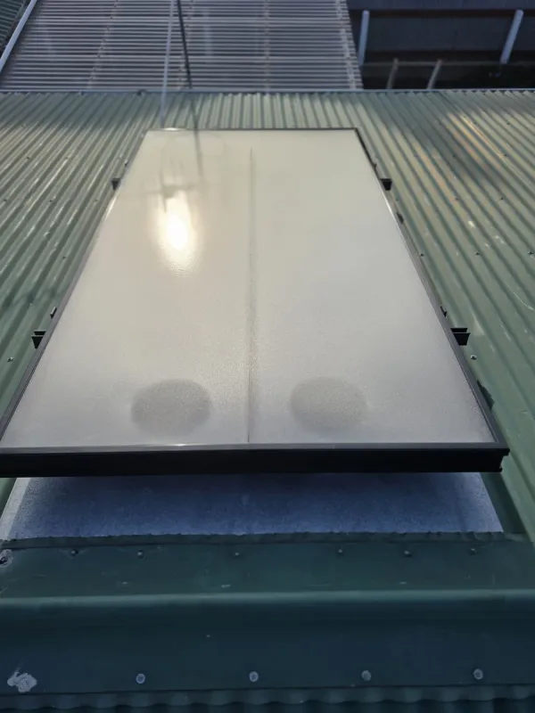 Close view of a glass solar air panel on a green corrugated roof