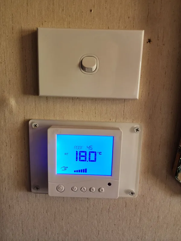 Close view of a digital wall controller showing roof and house temperature