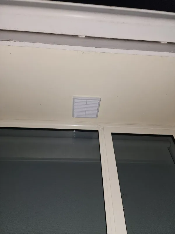 Fresh air intake grille fitted into an exterior eave above a window
