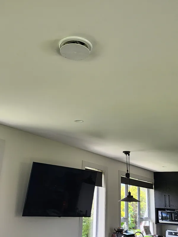 Round warm air outlet grille set into a hallway ceiling