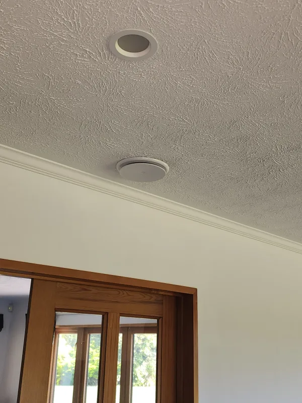 Round warm air outlet grille above a bedroom doorway