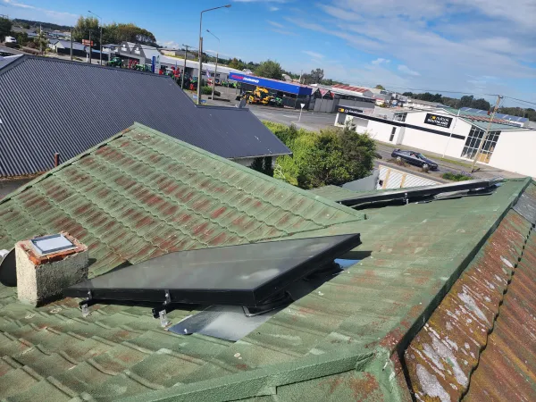 Solar air panel on a dark corrugated roof with farmland views behind