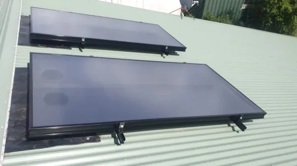 Solar air panel fitted into a dark tiled roof above a gutter line