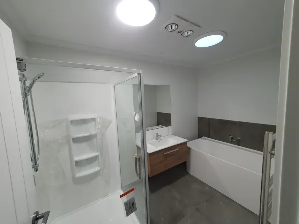 Bright white bathroom lit by two round sun tube diffusers in the ceiling