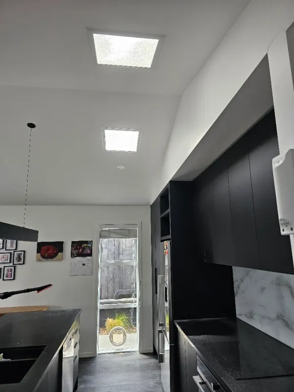 Dark modern kitchen lit by two square sun tube diffusers