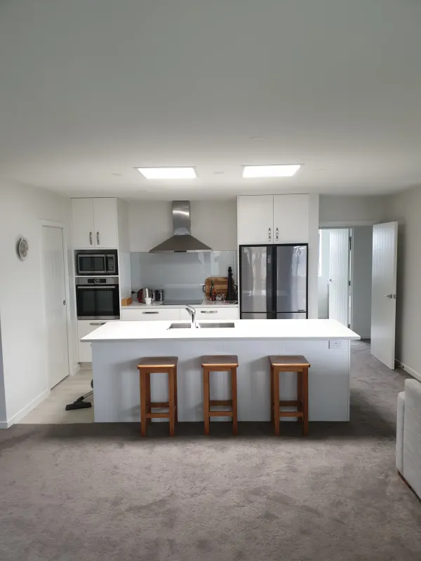 Open plan kitchen lit by two square sun tube diffusers above the island
