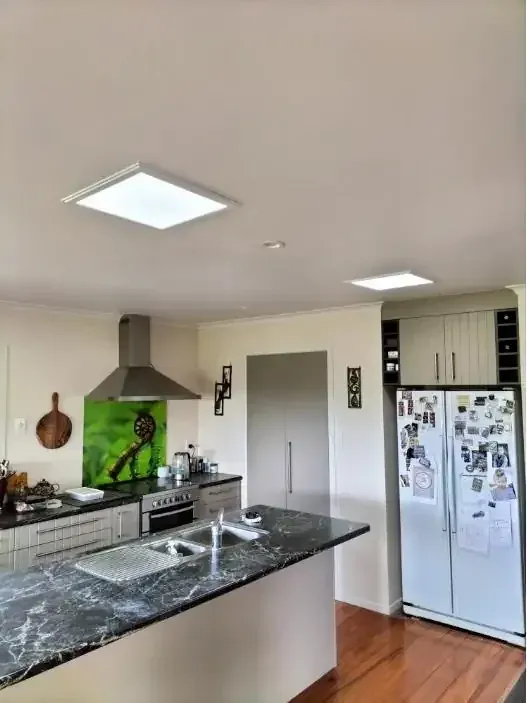 Kitchen with stone benchtops lit by square ceiling sun tubes